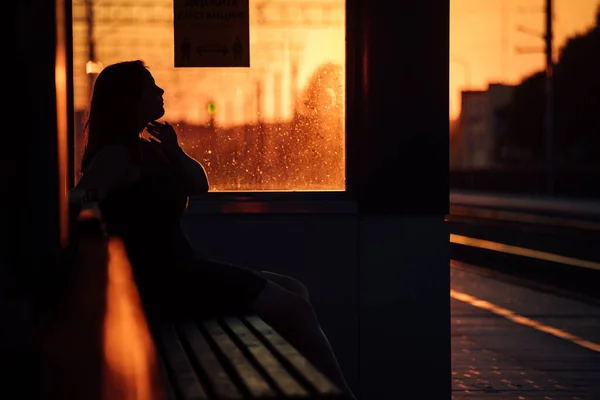 Девушка Сидит Железнодорожной Платформе Ждет Поезда Силуэт Человека Закате Против — стоковое фото