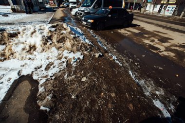 Çamurun içinde bir sürü sigara izmariti var. Yolun kenarına yasa dışı çöp yığını. İlkbaharda kar altında eriyen çöpler.