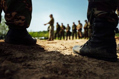 Ordu botları giymiş askerlerin ayakları kumların üzerinde duruyor. Uzun bir yürüyüşten önce eğitim alanı