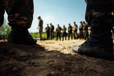 Ordu botları giymiş askerlerin ayakları kumların üzerinde duruyor. Uzun bir yürüyüşten önce eğitim alanı