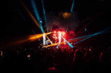 Konserdeki müzik grubu dansının mutlu hayranları. Sahne ışıklarının parlak ışığı binlerce seyirciyi aydınlatıyor.