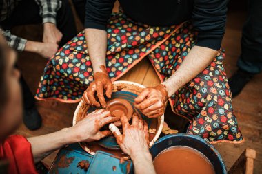 Bir çömlekçi ve bir öğrenci çömlekçi çarkında kilden yapılmış tabaklar yapıyorlar.