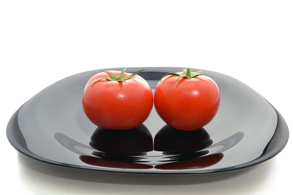 Tomatoes on a black plate — Stock Photo, Image
