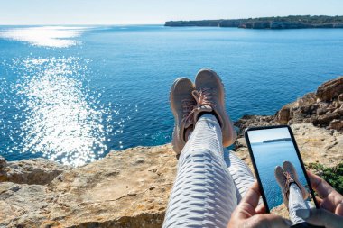 Deniz manzaralı manzaralı tatil konseptinin önünde kayalıklarda gezinen ayakları görmek, ayak fotoğrafçılığı rahatlamak seyahat tatilinin tadını çıkarmak.,