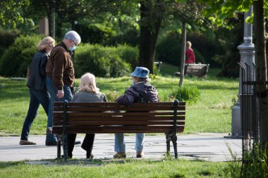 Parkta tıbbi maskeli yaşlı insanlar var.