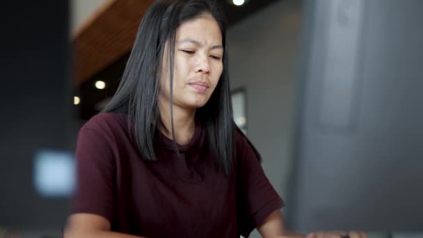 アジア系の女性はコンピュータの画面の前で長時間働いていて — ストック動画