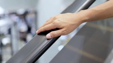 Alışveriş merkezinde yürüyen merdivende el ele tutuşan kadın.