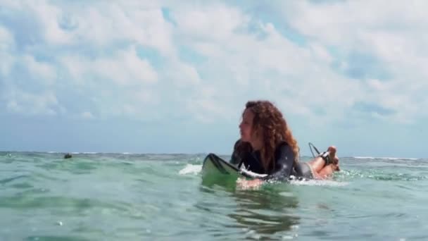 ビデオフッテージのサーファーの女の子オンホワイトサーフボードで青い海の写真からザ水でバリ島 — ストック動画