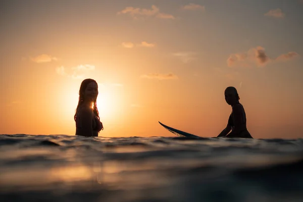 Bal Günbatımında Okyanusta Sörf Tahtasında Güzel Vücutlu Iki Sörfçü Kızın — Stok fotoğraf