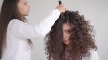 Saç stilisti, uzun siyah saçlı güzel bir kız için saç stili yapar.