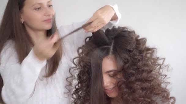 ヘアスタイリストは長い黒髪の若い美しい女の子のためのヘアスタイルを作ります — ストック動画