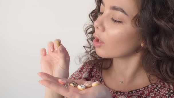 La chica sostiene rosquillas dulces en sus manos, lamentando no poder comerlas. — Vídeo de stock