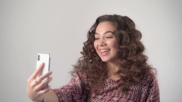 La chica se comunica emocionalmente por videollamada utilizando un teléfono inteligente moderno — Vídeos de Stock