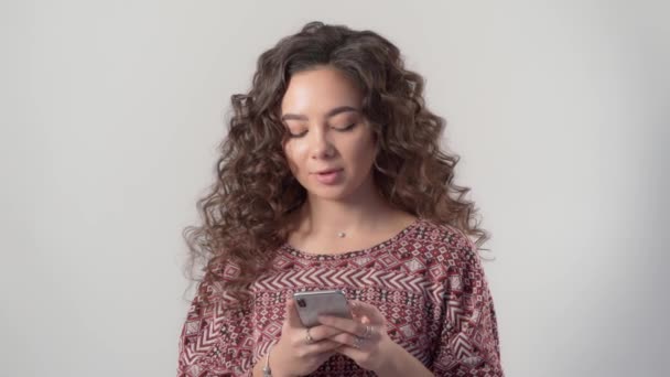 Una chica con un teléfono inteligente moderno mira a través de fotos en las redes sociales — Vídeos de Stock