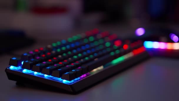 Um jogador de esports joga jogos em um teclado de jogos e mouse com luz de fundo RGB — Vídeo de Stock