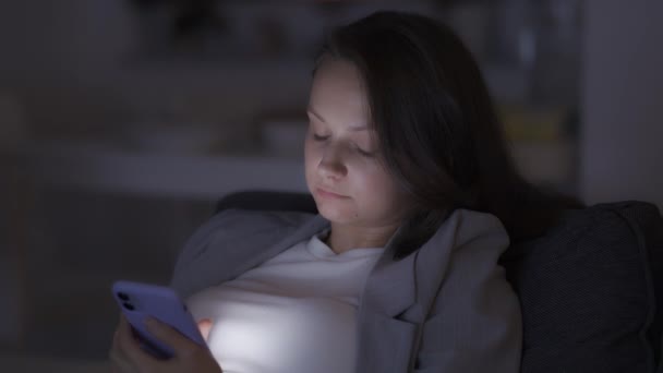 Одинокая женщина дома поздно ночью, глядя на экран смартфона и скучно — стоковое видео
