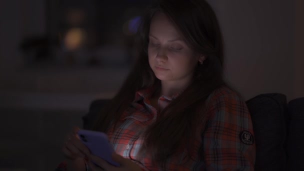 Samotna kobieta w domu późno w nocy, patrząc na ekran smartfona i znudzona — Wideo stockowe