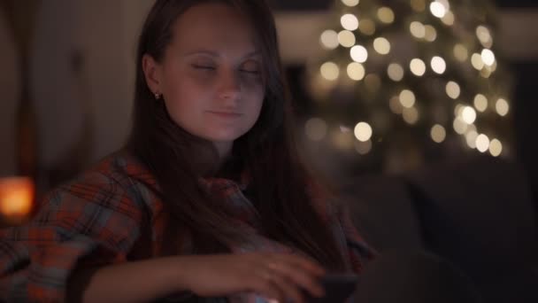 Женщина держит в руках современный смартфон и смотрит в камеру — стоковое видео