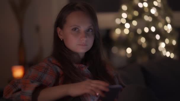 女性は手に現代的なスマートフォンを持っており、カメラを見て — ストック動画