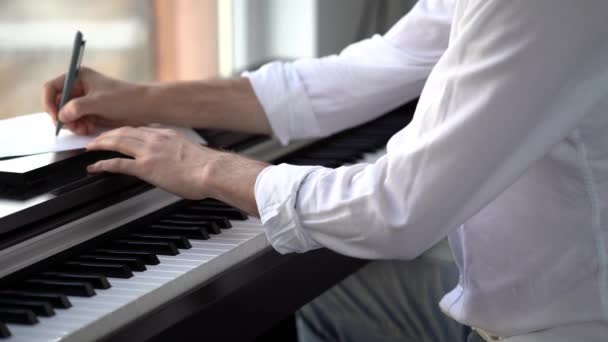 De componist speelt piano componeert muziek en schrijft deze op met noten — Stockvideo