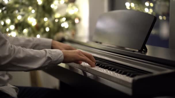 Un pianista musicista suona un pianoforte digitale accanto a un albero di Natale — Video Stock