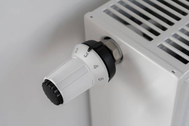 Merkezi ısıtma radyatörünü ayarlamak için kullanılan beyaz termostat odadaki sıcaklığı korumak için orta ekonomik modda ayarlanır