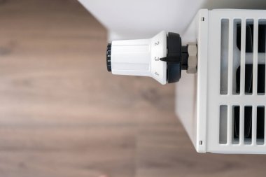 Merkezi ısıtma radyatörünü ayarlamak için kullanılan beyaz termostat odadaki sıcaklığı korumak için orta ekonomik modda ayarlanır