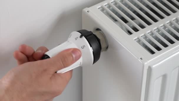 The man lowers the radiator temperature by turning the thermostat — Stock Video