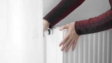 Bir adam soğuk ısıtıcının ısıtıcısına donmuş elleriyle dokunur ve ısıtma gücünü maksimum değerle arttırır. Isınma mevsiminde enerji tüketimini sınırlıyor. Enerji krizi..