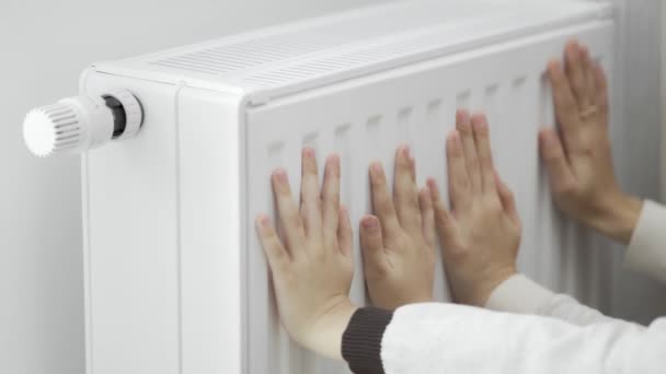 在寒冷的季节里 一个女人和一个小孩用他们冰冷的手掌碰了一下暖烘烘的暖气暖手 能源危机期间公寓的暖气 — 图库视频影像