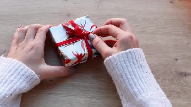 木のテーブルの上に小さなクリスマスプレゼントが女性によって開かれます トップ表示を閉じる — ストック動画
