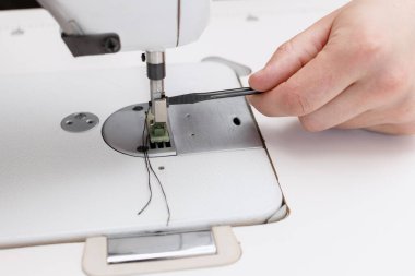 Adam dikiş makinesinde tutucuyu değiştiriyor.