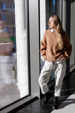 Çekici sarışın hippi şehrin geniş penceresinin yanında.