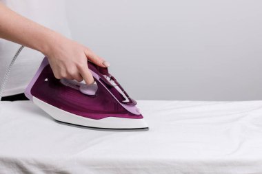 Gri arkaplanda beyaz bir tişört ütülüyor. yakın plan