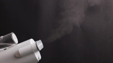 Elde taşınan buharlı gemi siyah bir zemine buhar salıyor.