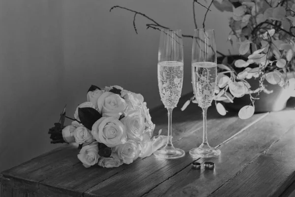 花嫁のバラの花束シャンパングラス結婚指輪木製の背景に 黒と白 — ストック写真