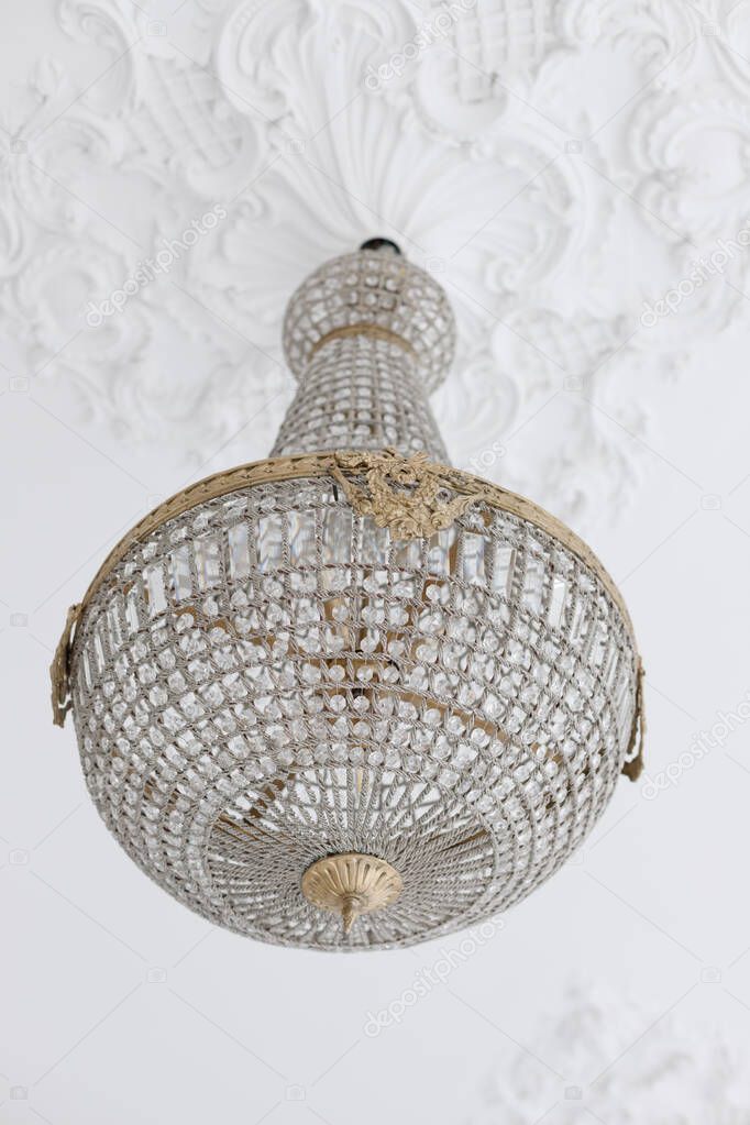 antique vintage chandelier on the ceiling with stucco. close-up