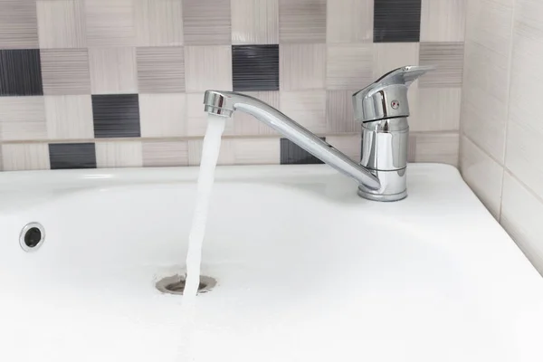 sink with open water tap on the background of tiles in the bathroom