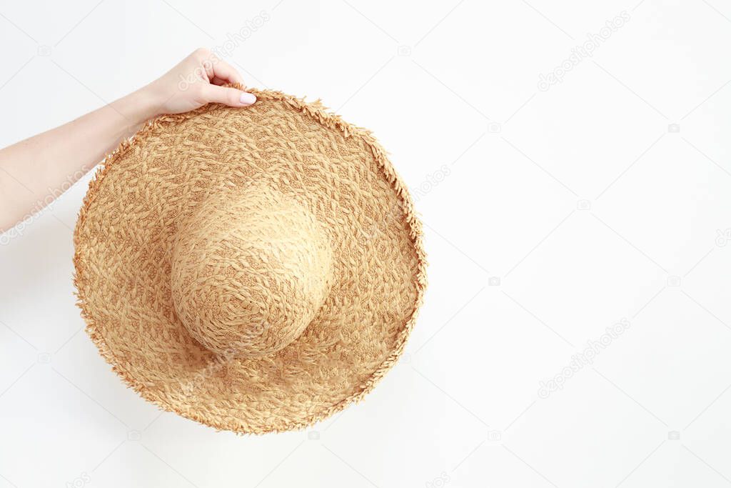 straw hat in hand on a white background. vacation summer