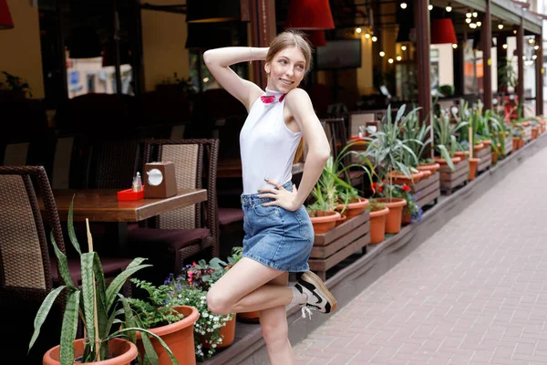 Yazın şehirde yürüyüş yapan, günlük giysiler içindeki genç bir kadının portresi.