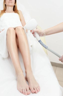 Diyot lazer aldırma, güzellik uzmanı güzel kadın bacaklarındaki kılları aldırır, pürüzsüz cilt için saç aldırma, güzellik stüdyosunda ya da klinikte lazer ameliyatı, vücut bakımı epilasyonu tedavisi..