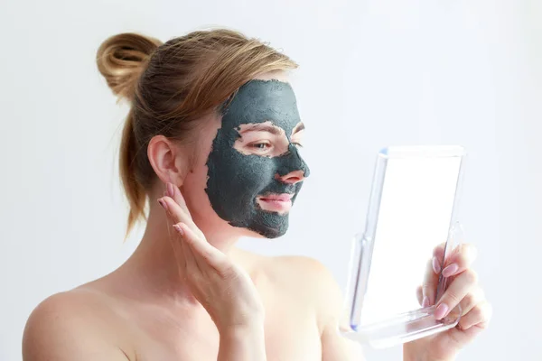 Vrouw Glimlachen Een Cosmetische Klei Masker Haar Gezicht Kijkt Spiegel — Stockfoto