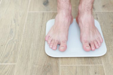 Bir adam zemin kattaki terazide duruyor. Yakın plan.