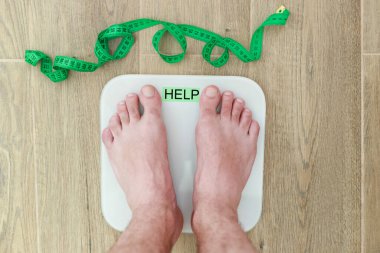 Bir adam zemin kat manzarasında bir terazide duruyor. kilolu