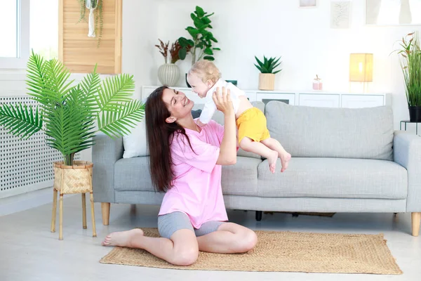 Bir kadın oturma odasında kucağında bir bebek tutuyor. üst