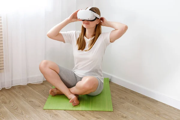 VR Oculus 'daki kadın spor paspasının üzerinde antrenmana hazırlanıyor.