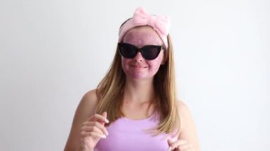 woman in a cosmetic mask on her face dancing on a gray background