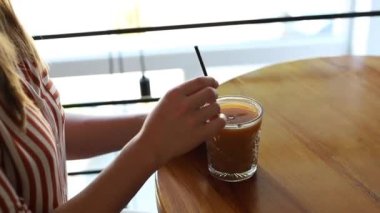 woman with chilled coffee drink in coffee shop