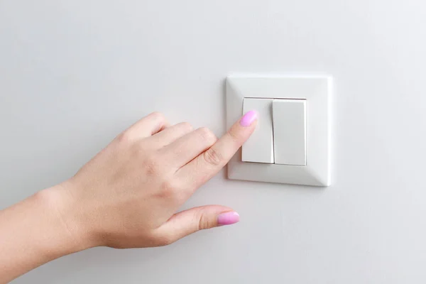 close-up woman turns on the switch on the wall. home light switch