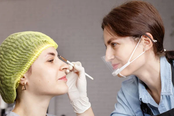 beautician paints eyebrows with henna to a woman. correction and lamination of eyebrows and eyelashes. beauty saloon